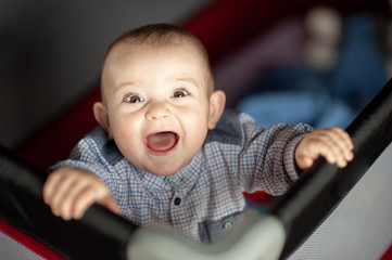 baby screeching inside his park looking at his mother