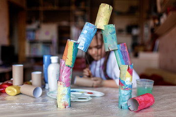 Cute girl coloring toilet paper rolls to use them like paper blocks to build a tower