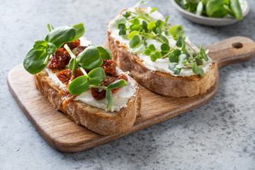 Sandwich on toast with fresh radish microgreen and cream cheese on grey background. Close up.