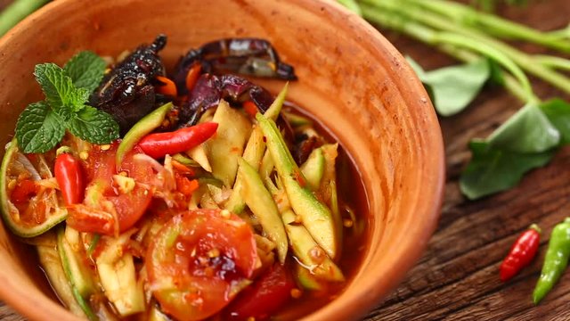 Thai food: Som Tam is popular Thai food. Mango salad with dried shrimp, salty crab, chili, tomato and spicy herbs. Served with vegetables. Still life shoot in studio, Clean food good taste concept.