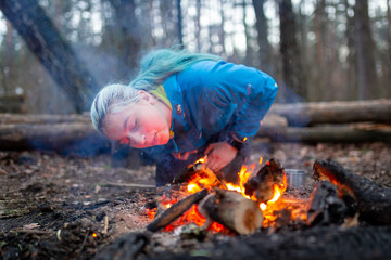 Woman blowing a fire with sparks in forest outdoor camping