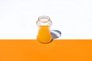 horizontal view glass with orange juice on white and orange background
