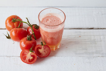Tomatoes fresh juice in the glass with ingredients on the light background