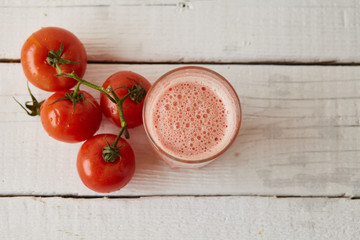 Tomatoes fresh juice in the glass with ingredients on the light background