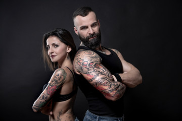 coppia di ragazzi tatuati, che mostrano i loro tatuaggi e i loro muscoli, isolati su sfondo nero