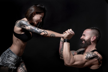 coppia di ragazzi tatuati, fanno un aprova di forza, , isolati su sondo nero