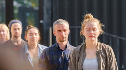 A group of young people meditate outdoors in a park. 