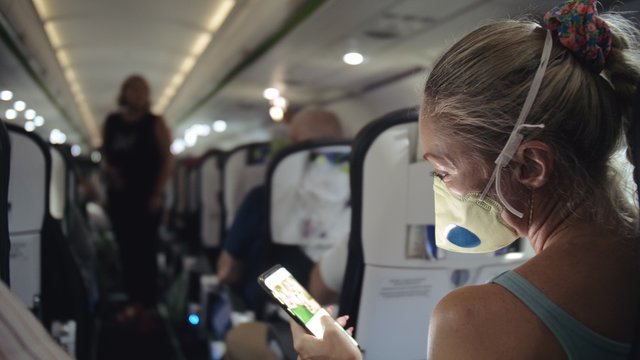 Woman Travel Tourist Caucasian At Plane Aircraft With Wearing Protective Medical Mask. Read Shock News About Coronovirus At Smartphone Mobile. Virus Coronavirus Epidemic Sars-cov-2 Covid-19 2019-ncov.