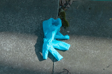 a close up view of blue synthetic hygiene gloves discarded in the darkness of the shadows during...