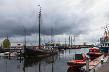 Port in the city of URK in Holland. In the harbor, boats are moored and in the background there is a blue sky with white clouds. - obrazy, fototapety, plakaty