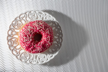 Pink Doughnut in a Vintage White Plate on a White Bakground