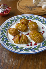 Hasselback potatoes with yoghurt sauce and topped with pomegranate seeds. 