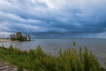 View of the sea and cloudy sky with clouds in the city of Urk in Holland. In the background are windmills.