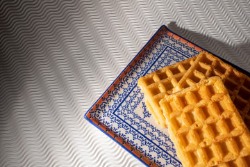 Close view of waffles in a blue plate isolated on a white background