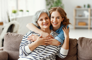 Happy senior woman with daughter hugging at home