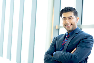 Portrait Handsome confident businessman wearing suit standing Successful businessman with folded arms  standing over office background. caucasian looking at camera. joyful smile with copy space.