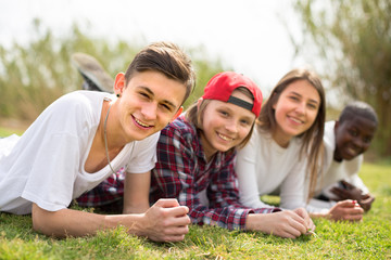 multinational modern teens lie in the park on the grass