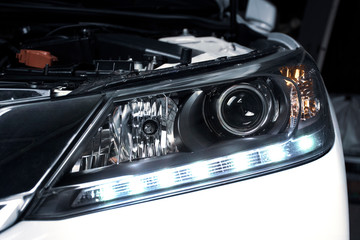 Close up details of projector lens headlights and daytime running light technology in a car.