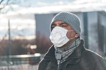 Headshot of a man covering his face with a medical mask to protect his nose and mouth posing...