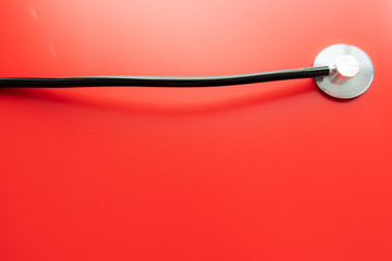 Close up of a stethoscope isolated on red background