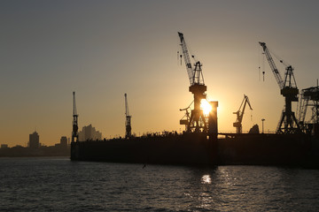 Obraz premium Silhouette vom Hamburg Hafen bei orangen Sonnenaufgang Himmel 