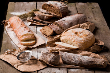 Assortment of baked bread and bread rolls on wooden table background.