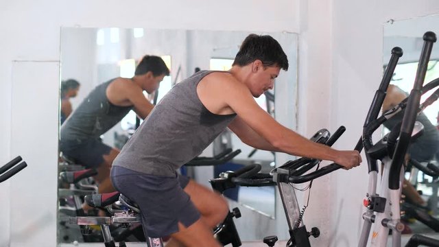 Man doing bike exercise in the gym, exercising his legs doing cardio training.