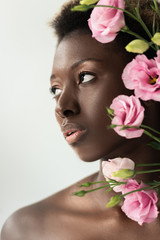 beautiful naked african american girl with pink eustoma flowers isolated on grey