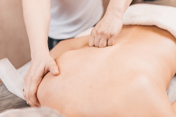 Fototapeta na wymiar Back massage technique - close-up of a female masseur's hands