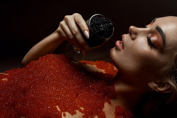 Beautiful young girl in a bath with red caviar - obrazy, fototapety, plakaty