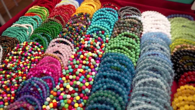 Close-up. Many multi-colored bead bracelets are on the counter at the night market. Sale of bracelets on hand.
