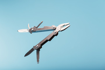 The multitool multi-function tool hovers on a blue background. The concept of an expanded multi-tool with free space.