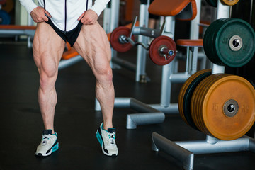 Fototapeta na wymiar Male muscular athlete bodybuilder show thigh muscles.