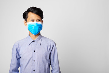 Asia man wearing surgical mask  covering mouth and nose looking to copy space. epidemic corona virus protection.