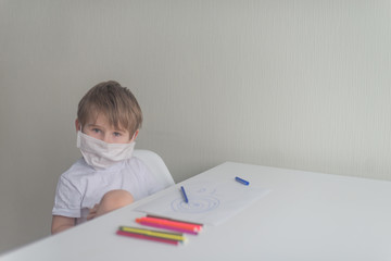 Naklejka premium Little boy in medical mask sits on the chair near the table