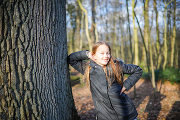 Fototapeta premium A old girl leans on the trunk of a huge tree