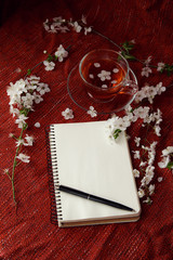 Time for tea, empty notebook, pen and cherry flowers on table