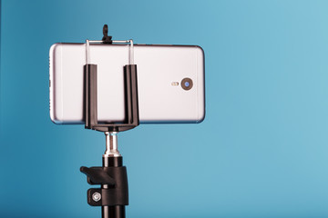 Smartphone on a tripod as a photo-video camera on a blue background. Record videos and photos for your blog.