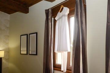bonito vestido de niña colgado junto a una ventana de la habitación