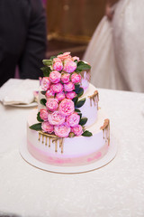 Delicate pink and white three tiered wedding cake decorated with roses.