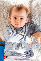 Naklejka premium Adorable funny one year old lie on a carpet with water bottle. Looking into camera.