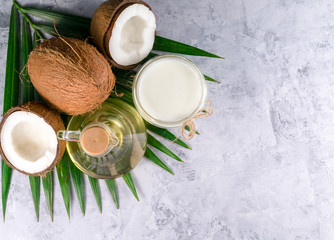coconuts, palm leaves and coconut oil on a gray background