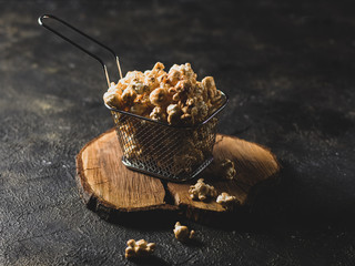 Popcorn in a basket on a dark background and a wooden stand in the dark style horizontal arrangement