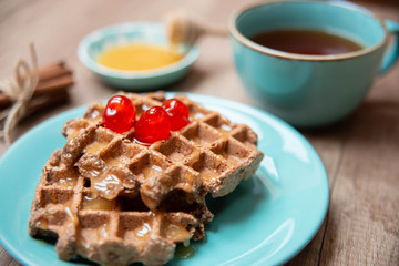 Healthy breakfast waffles with honey and coctail cherries