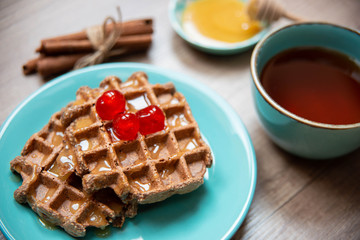 Healthy breakfast waffles with honey and coctail cherries