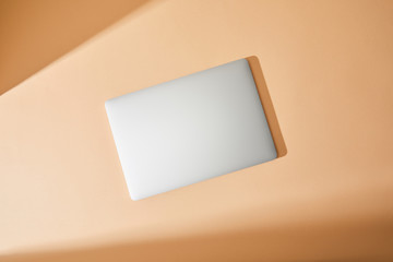 top view of closed white laptop on beige background