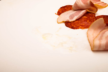 Slices of bacon and sausage on a white background. Close up.