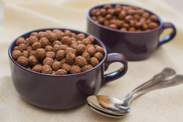 Chocolate balls in a purple porcelain cup on a white napkin.