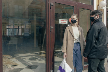 Portrait of couple in love in a surgical bandage on a background of a closed cafe