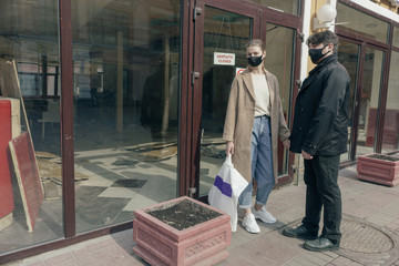 Portrait of couple in love in a surgical bandage on a background of a closed cafe